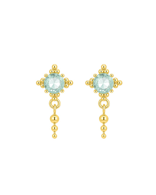 A pair of gold dangle earrings featuring a round light blue-green gemstone in a floral cluster setting, with a dangling beaded chain below, shown on a plain white background.